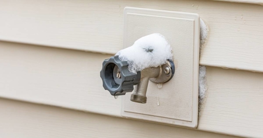 Outdoor water spigot covered in snow during winter